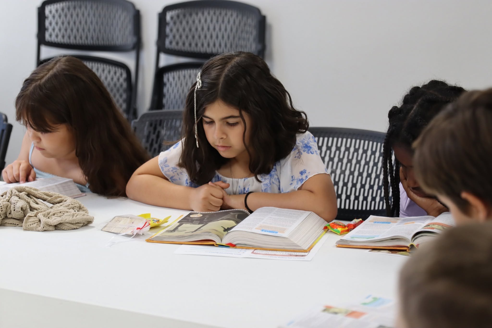 Children seated at a table reading books and doing a class activity