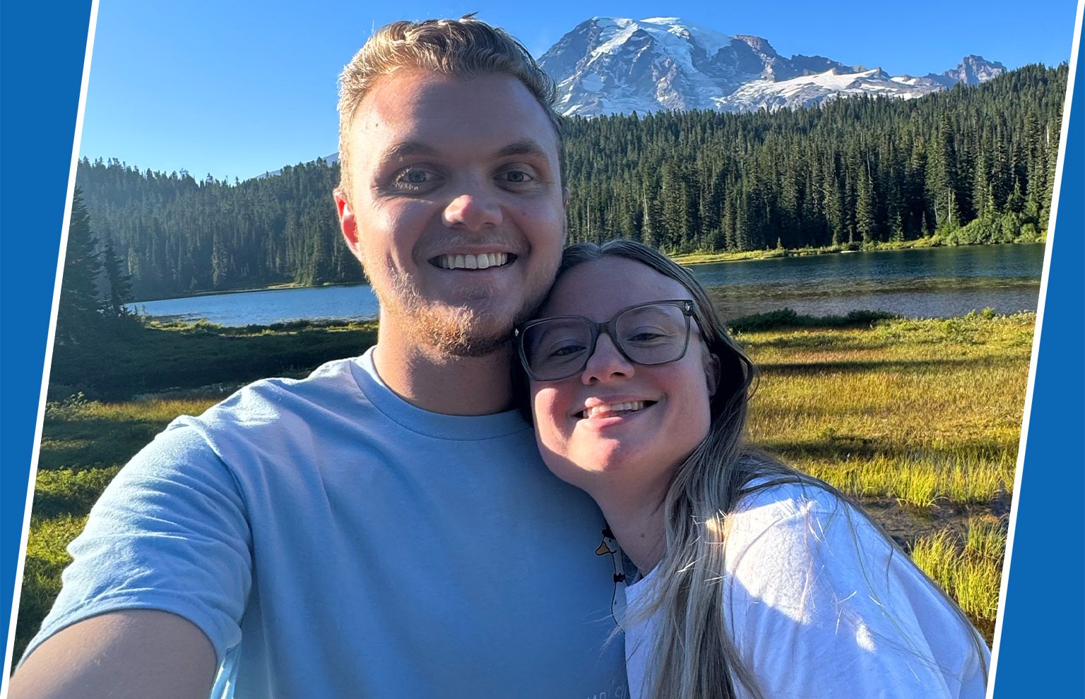 Smiling young man and young woman taking a selfie in front of a mountain lake
