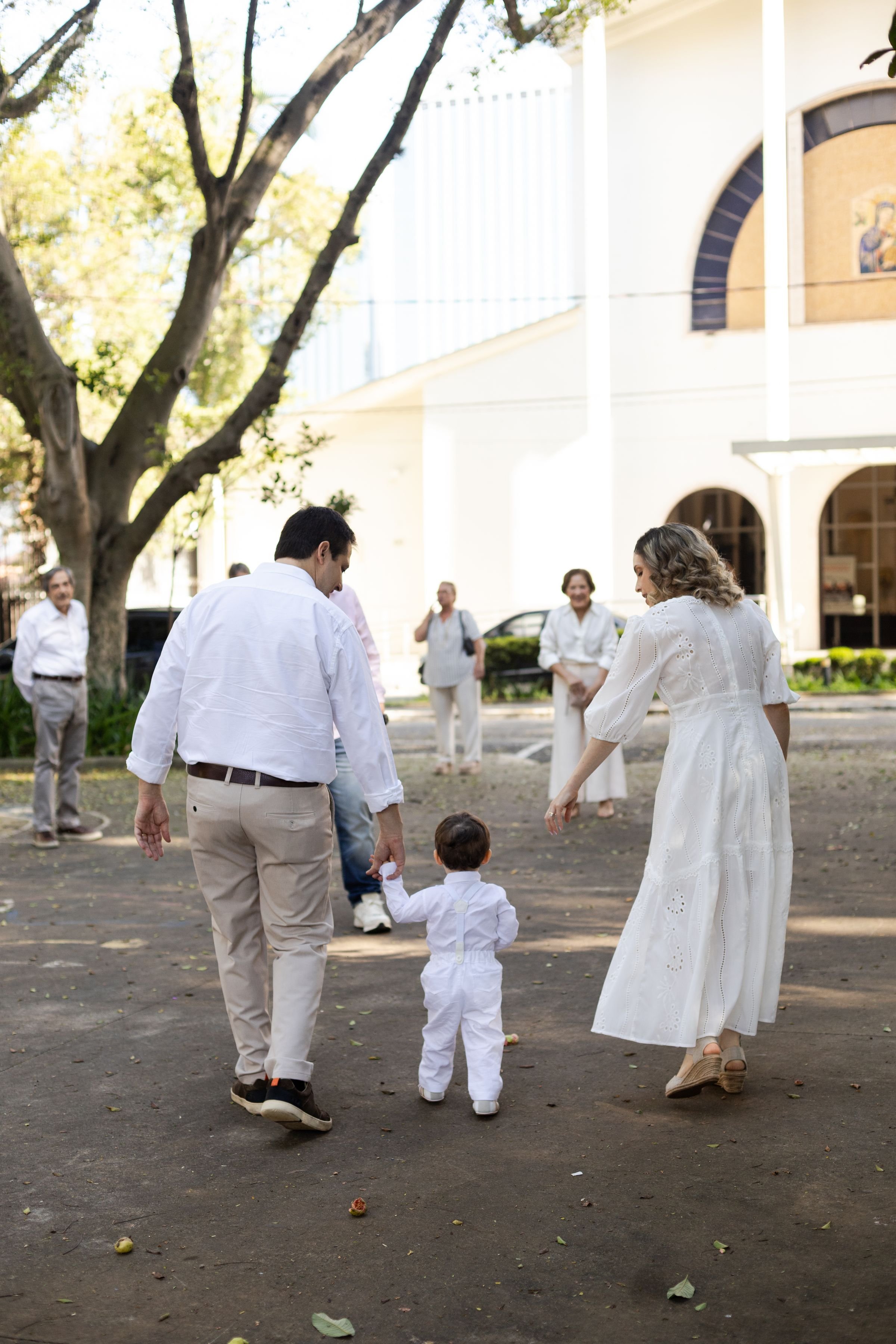 Family walking hand in hand with a toddler toward a white church building